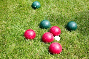 Red and green bocce balls on grass.