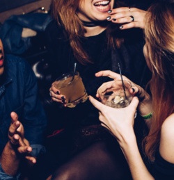 People having fun at a party while sitting down with drinks.